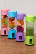 Four colorful portable blenders with fruits inside on a wooden surface.