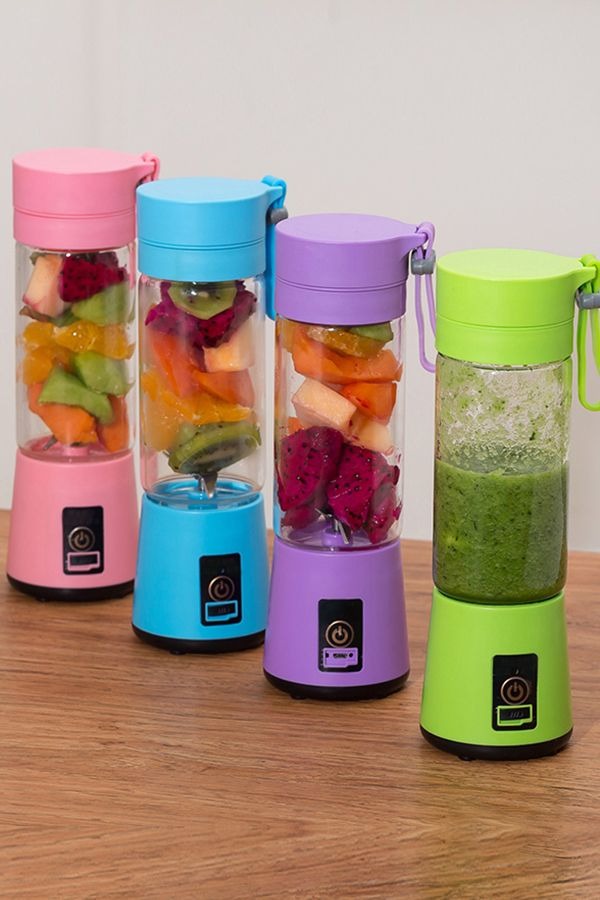 Four colorful portable blenders with fruits inside on a wooden surface.