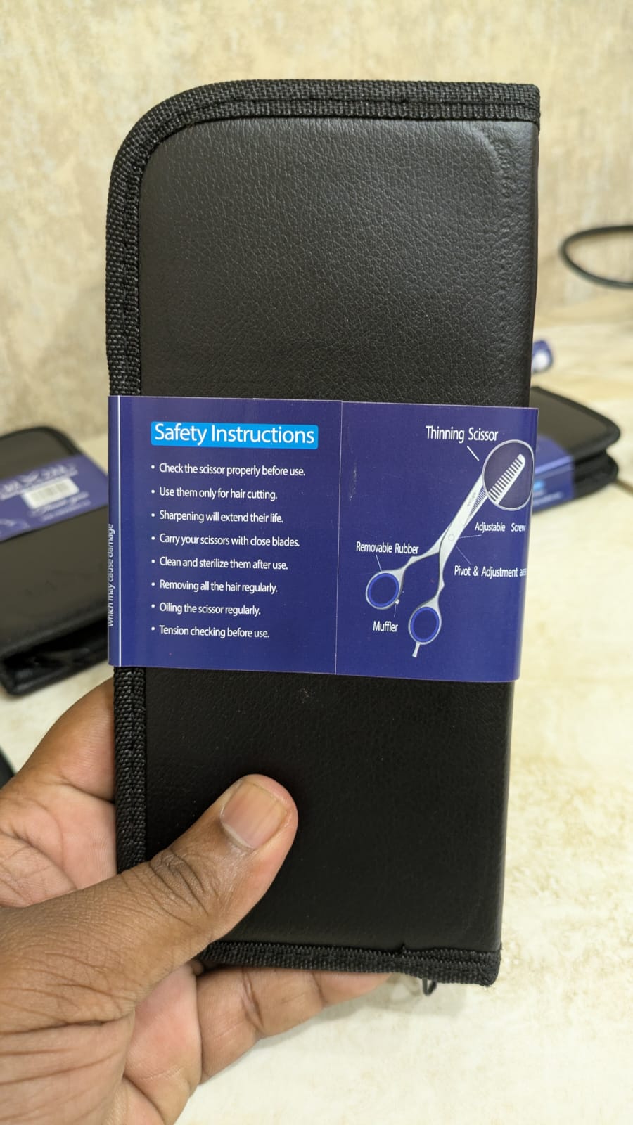 Black pouch with safety instructions label held by a hand on a beige background