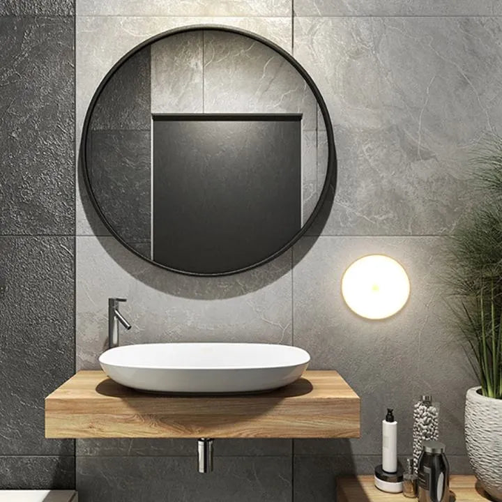 Bathroom with round mirror, sink, and decorative elements on a gray tiled wall.