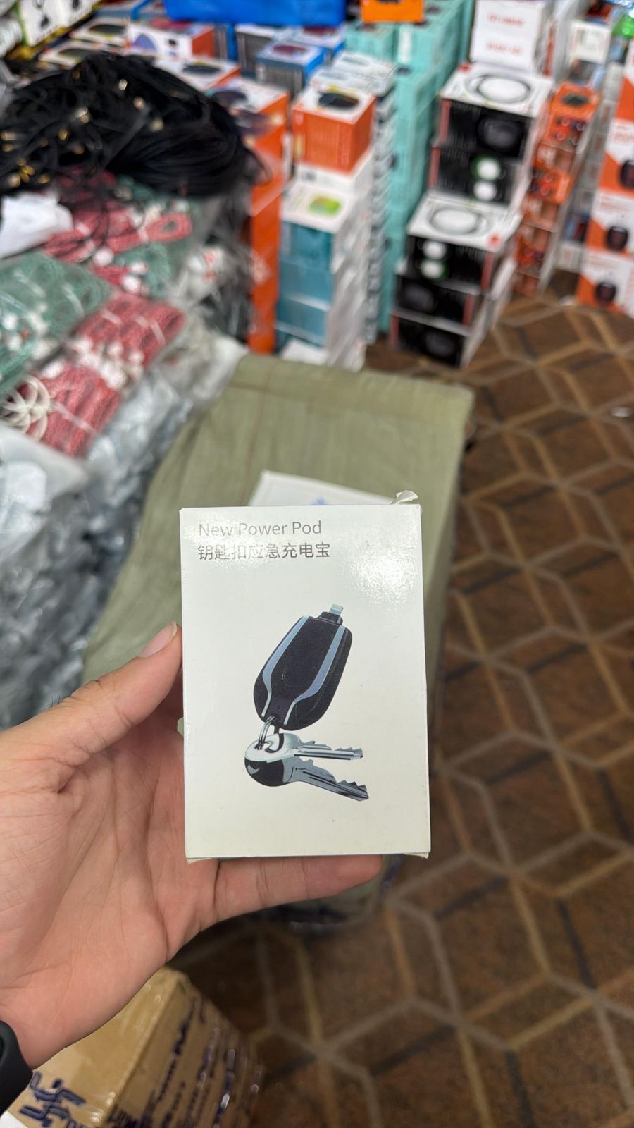 Hand holding a small product packaging with a design on a store floor background