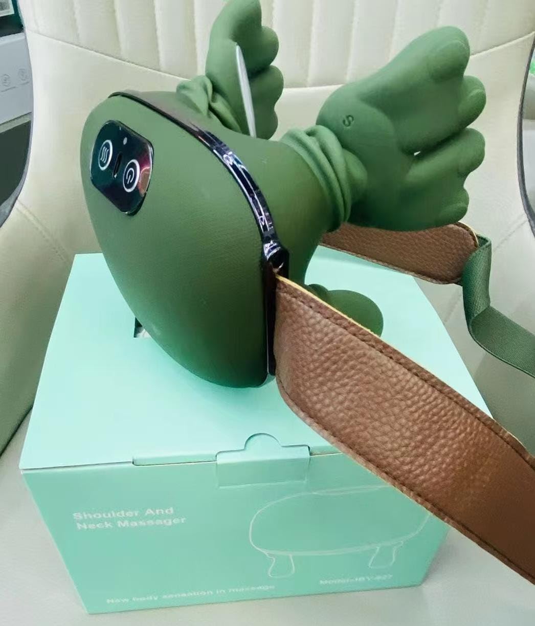 Green massage device with brown strap on a light green box