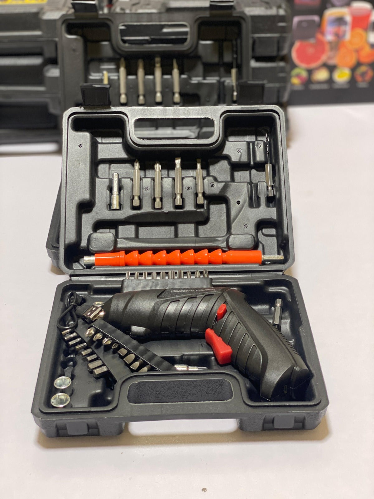 Open tool case with drill and accessories on a white background