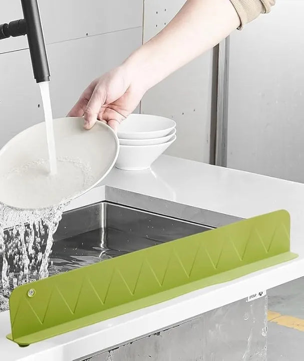 Person washing a bowl with a green kitchen sink strainer in a kitchen setting.