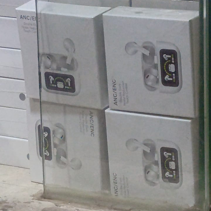 Stack of boxes containing wireless earbuds with visible branding on a glass surface.