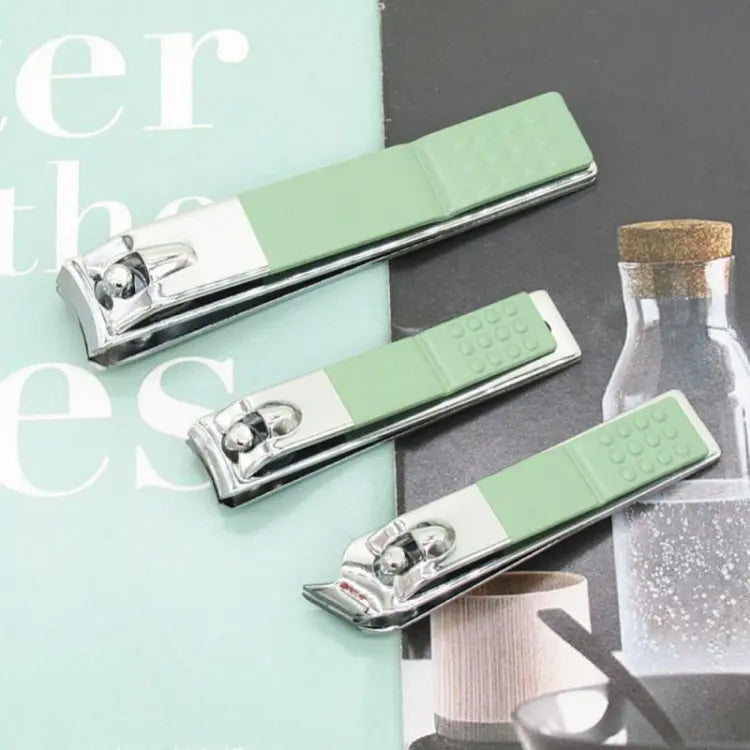 Three green nail clippers on a magazine page with blurred text