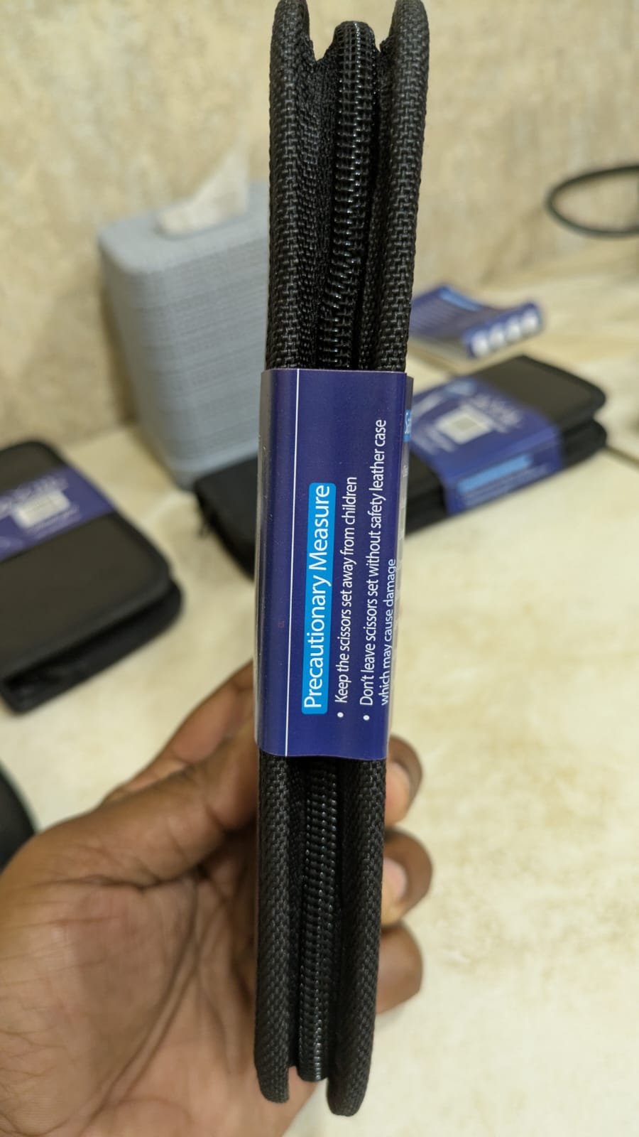 Black braided cable with blue label held by a hand on a blurred background